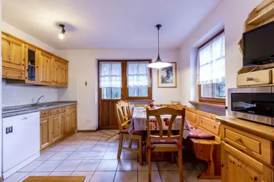 a kitchen with wooden cabinets and a table and chairs at El Tobià in Campitello