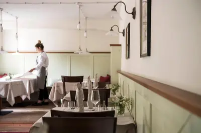 a woman standing in a dining room with tables at Hotel Weingut Stroblhof in Appiano sulla Strada del Vino