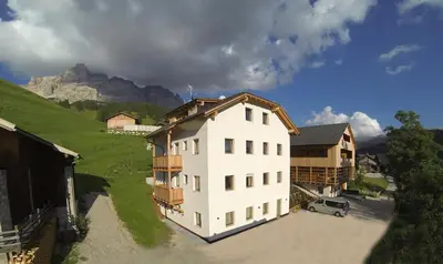 a large white building with a mountain in the background at Ciasa Soplà in San Cassiano