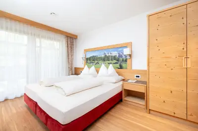 a bedroom with a large white bed with white pillows at Ciasa Soplà in San Cassiano