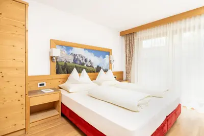 a bedroom with a large bed with white pillows at Ciasa Soplà in San Cassiano