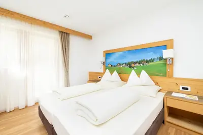 a bedroom with a large white bed with white pillows at Ciasa Soplà in San Cassiano