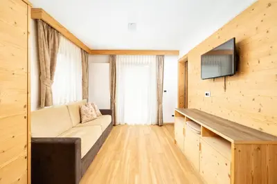 a living room with a couch and a flat screen tv at Ciasa Soplà in San Cassiano
