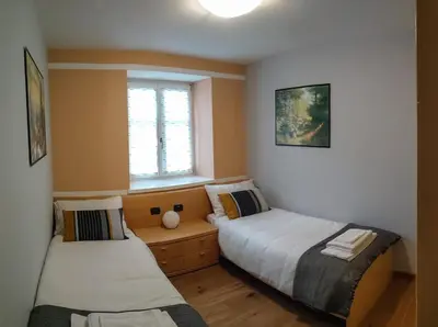 two beds in a small room with a window at Casa Zone in Tesero