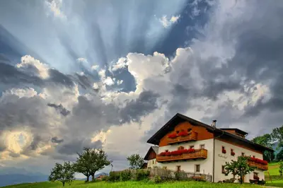 a house on a hill under a cloudy sky at Huberhof Morgensonne in Terento