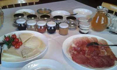 a table topped with bowls of meat and other foods at Huberhof Morgensonne in Terento