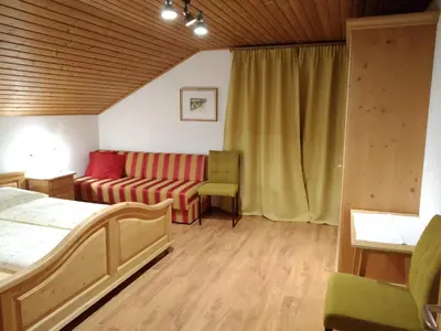 a bedroom with a bed and a couch at Huberhof Morgensonne in Terento