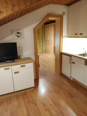 a kitchen with white cabinets and a wooden floor at Huberhof Morgensonne in Terento