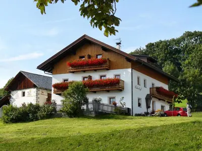 a large white house with red flowers on it at Huberhof Morgensonne in Terento