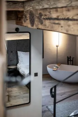a bathroom with a tub and a bedroom with a bed at Hotel Ansitz Steinbock in Villandro