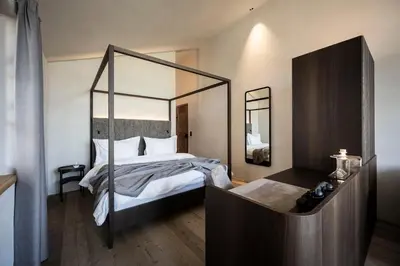 a bedroom with a canopy bed with a mirror at Hotel Ansitz Steinbock in Villandro