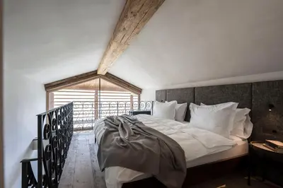 a bedroom with a white bed with a large window at Hotel Ansitz Steinbock in Villandro