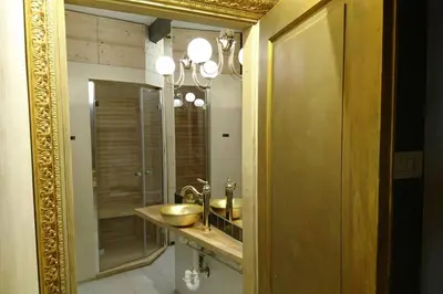 a bathroom with a gold mirror and a sink at Ugo Art Lodge Classic in Bolzano