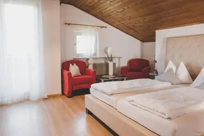 a bedroom with a bed and two red chairs at Guesthouse Christine in Marlengo