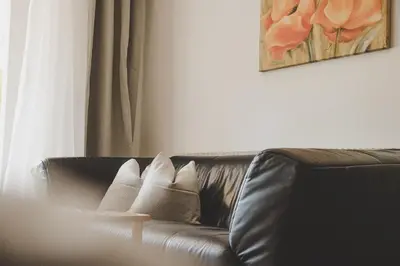 a living room with a leather couch with pillows at Guesthouse Christine in Marlengo