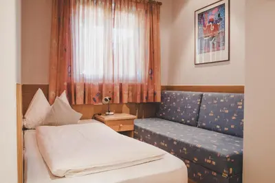 a bedroom with a bed and a couch and a window at Guesthouse Christine in Marlengo