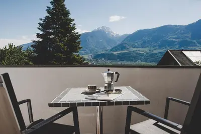 a table with a coffee maker and two chairs on a balcony at Guesthouse Christine in Marlengo