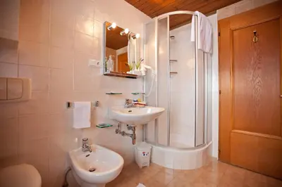 a white bathroom with a sink and a shower at Apartaments Galina in Selva di Val Gardena