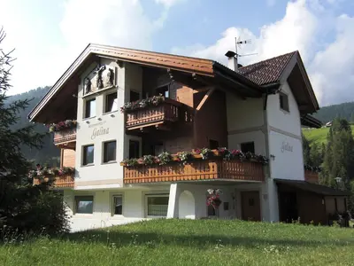a building with a balcony with flowers on it at Apartaments Galina in Selva di Val Gardena