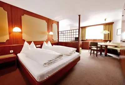 a hotel room with a bed and a dining room at Residence Bacher in Valdaora