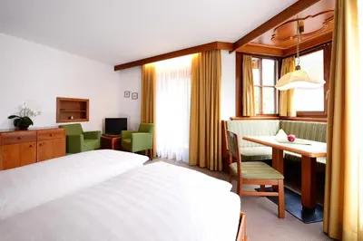 a hotel room with a bed and a desk and a table at Residence Bacher in Valdaora