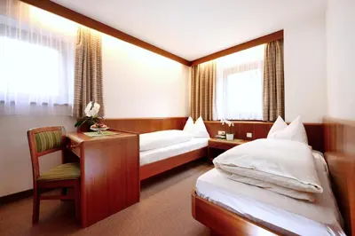 a hotel room with two beds and a desk at Residence Bacher in Valdaora