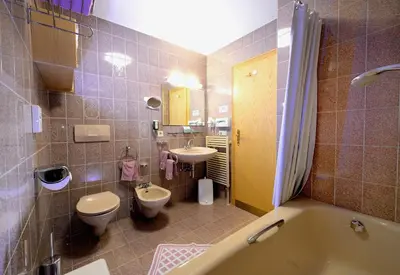 a bathroom with a tub and a toilet and a sink at Residence Bacher in Valdaora