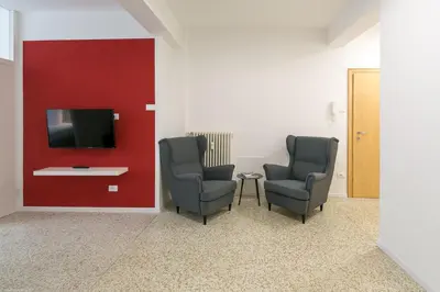 two chairs and a tv in a room with a red wall at Apartment Duomo in Bolzano