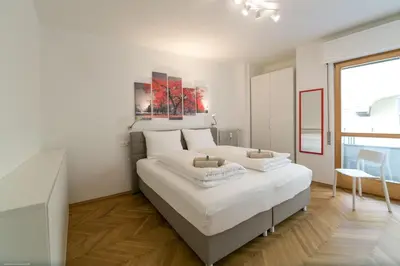 a white bedroom with a large bed and a table at Apartment Duomo in Bolzano