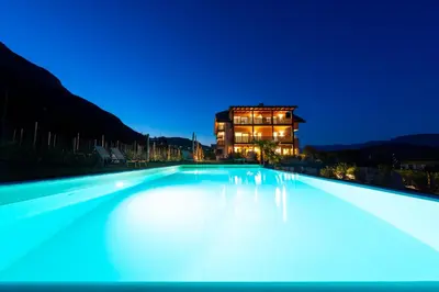 a large swimming pool with a building in the background at Sonnenhof Tramin - Adults Only in Termeno