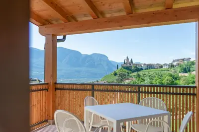 a table and chairs on a deck with a view of the ocean at Sonnenhof Tramin - Adults Only in Termeno