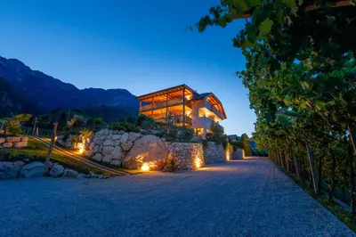 a house on a hill with lights on a road at Sonnenhof Tramin - Adults Only in Termeno