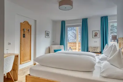 a white bedroom with two beds and a window at Hotel Berghaus Rosengarten in Nova Levante