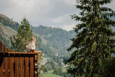 a building with a balcony in the woods at Hotel Berghaus Rosengarten in Nova Levante