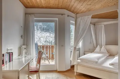 a bedroom with a bed and a desk and a window at Hotel Berghaus Rosengarten in Nova Levante