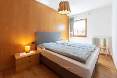 a bedroom with a bed and a table with a lamp at Tobià de Barat in Pozza di Fassa