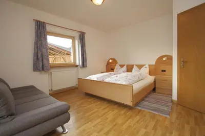 a bedroom with a bed and a couch and a window at Paderlafoderhof in Laion