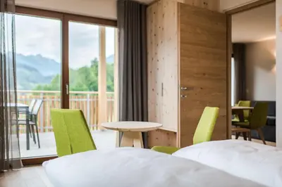 a hotel room with two beds and a table and chairs at Aparthotel Abiná Lana Höhe in Lana