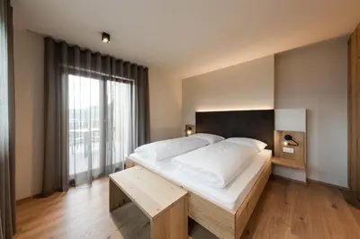 a bedroom with a large bed and a large window at Aparthotel Abiná Lana Höhe in Lana