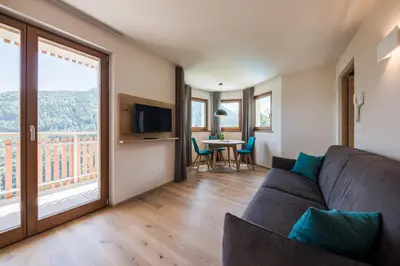a living room with a couch and a table with chairs at Aparthotel Abiná Lana Höhe in Lana