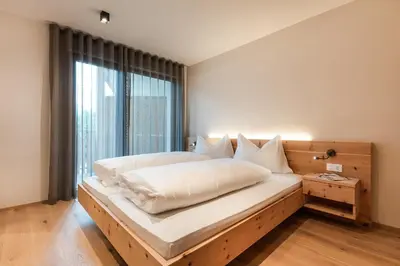 a large bed in a room with a large window at Aparthotel Abiná Lana Höhe in Lana