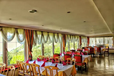 a restaurant with tables and chairs and large windows at Panoramahotel Unterinnerhof in Auna di Sotto
