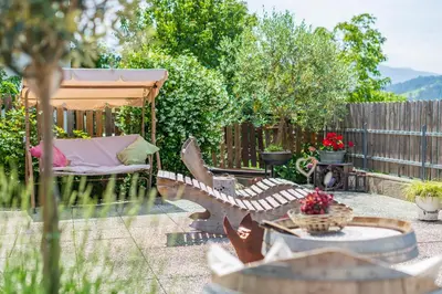 a backyard with a bench and an umbrella and a table at Haus Karin view in Brixen