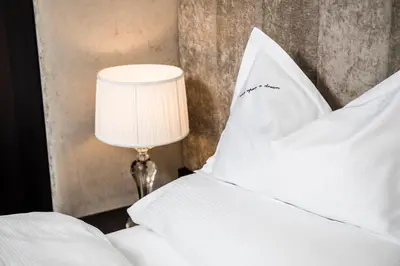 a bed with white pillows and a table lamp at Prunner Luxury Suites - Adults Only in Schenna