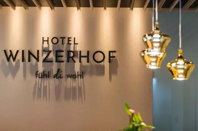 a sign on a wall with two chandeliers at Hotel Winzerhof in Termeno