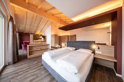 a bedroom with a large white bed and a desk at Hotel Winzerhof in Termeno