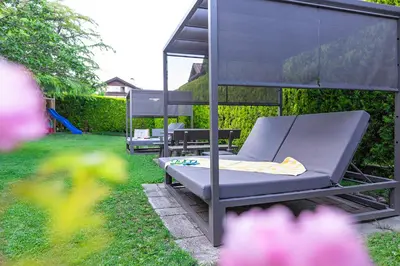 two lounge chairs in a yard with a canopy at Hotel Winzerhof in Termeno