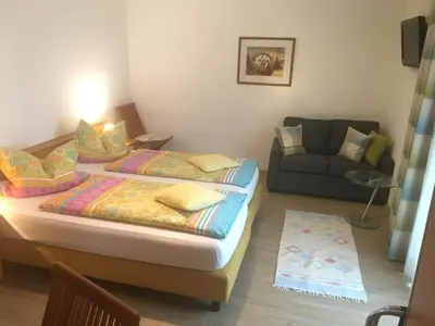 a bedroom with two twin beds and a couch at Garni Rebhof in Nalles
