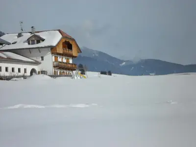 a house on top of a snow covered field at Appartamenti Stauderhof in Villabassa
