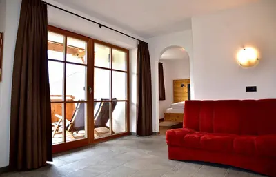 a living room with a red couch and a balcony at Putzerhof in Funes
